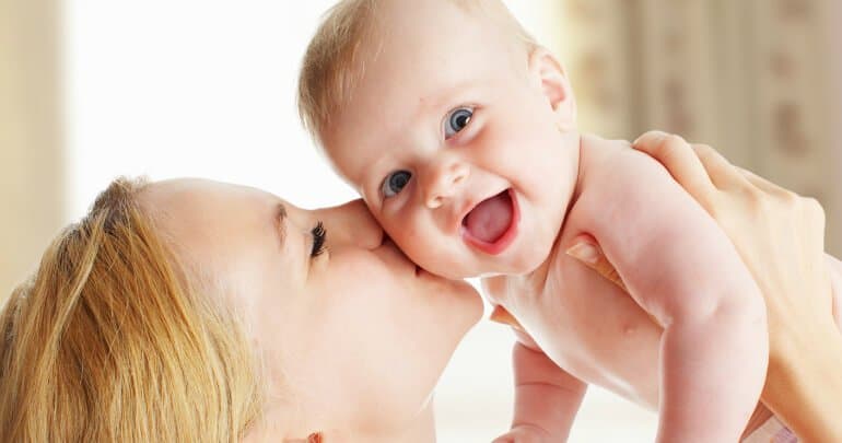 Mother kissing her smiling baby